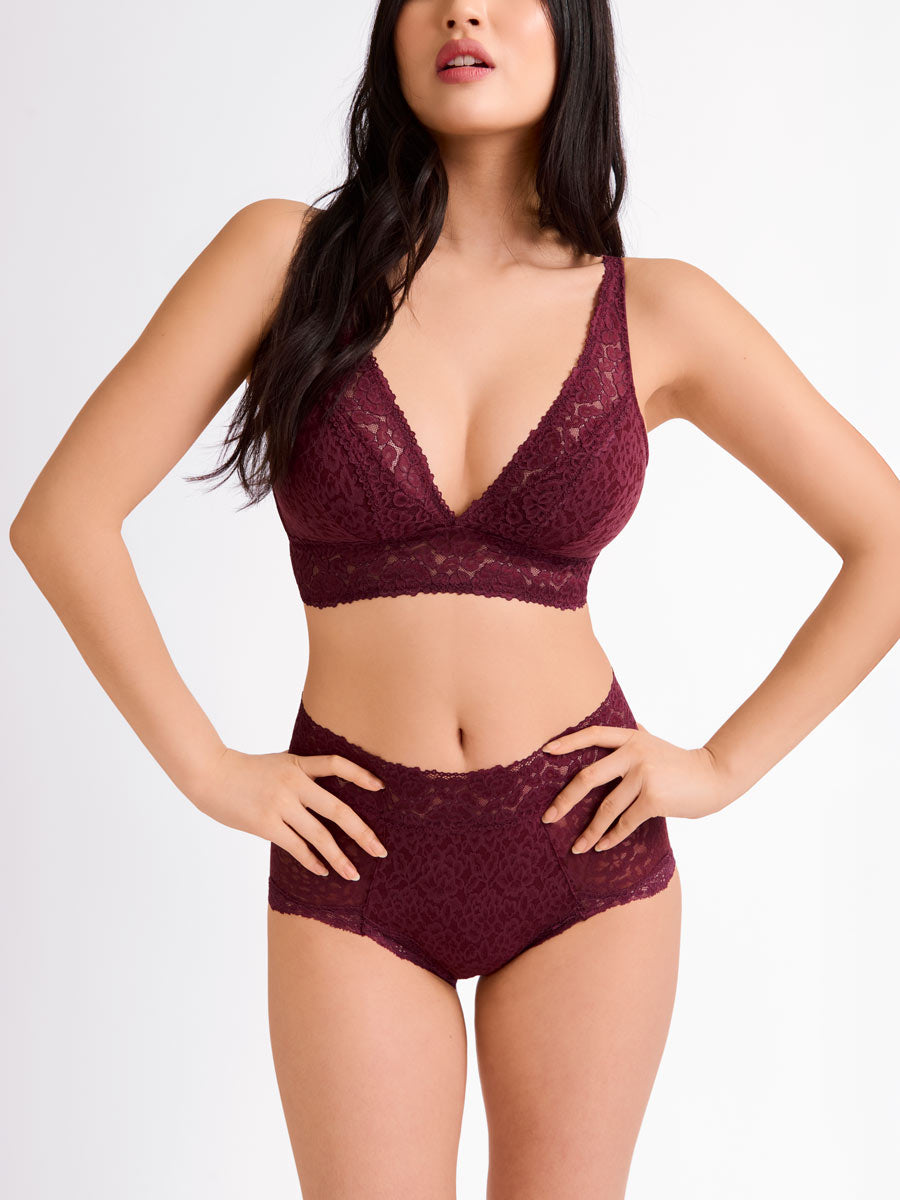 Woman wearing a burgundy/maroon lace bra and shortie on a white background